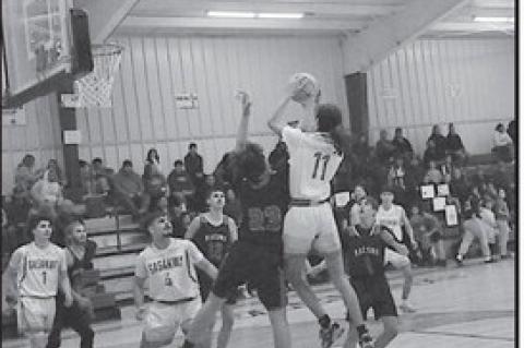 Sasakwa Viking Kaisyn Shaw jumps above the Macomb defenders for the basket. Staff Photo by Bill Anderson
