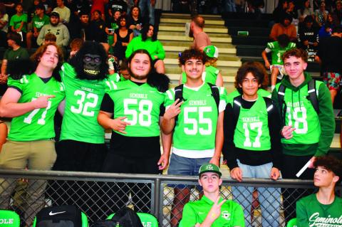 Above left, two shy youngsters peep over the railing at the gymnasium during Seminole High School’s Homecoming pep rally Friday afternoon. Right, members of the SHS football squad (plus a possible primate) pose during the rally. —Staff photos by Andy 